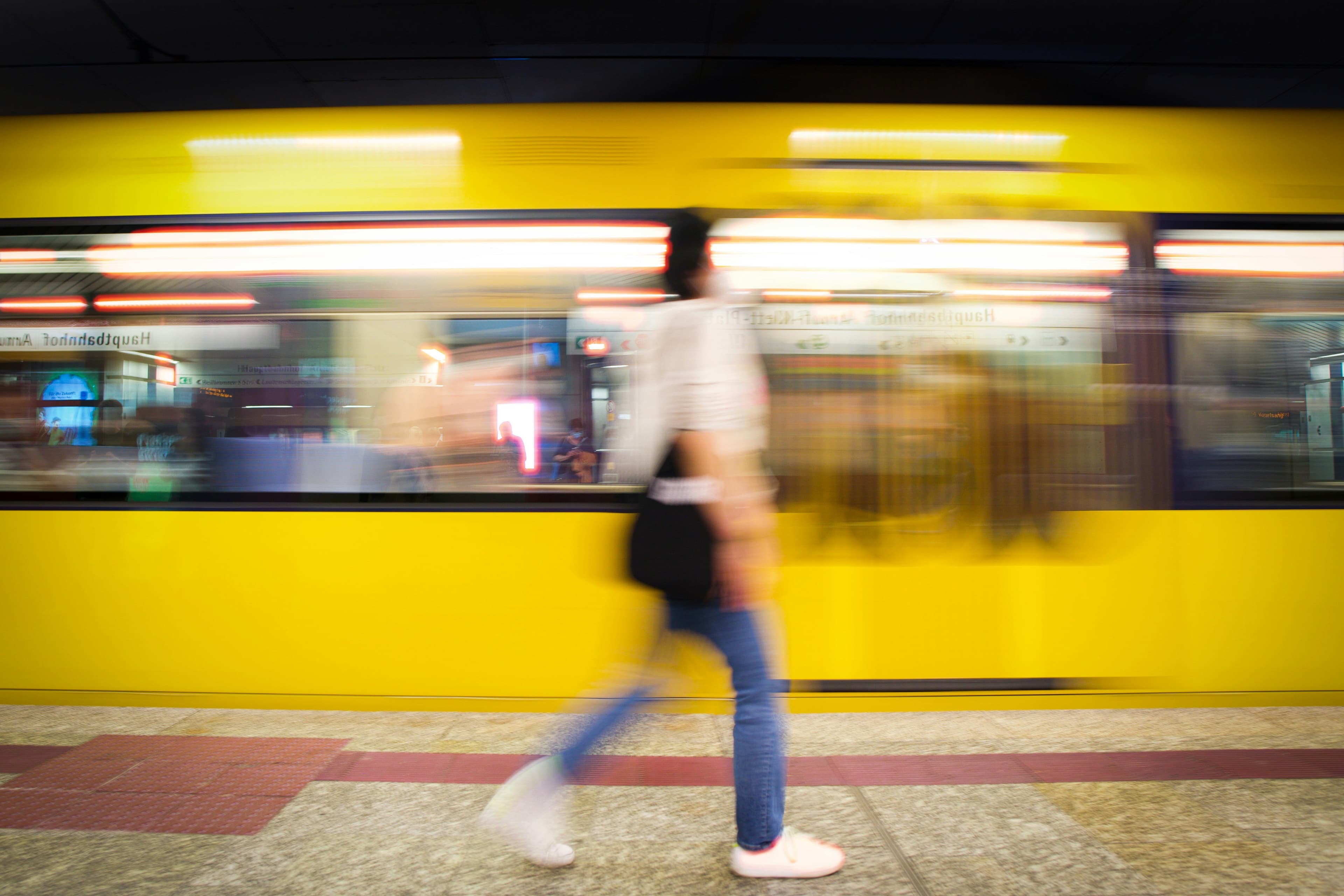 A figure crossing a station platform with a yellow train in motion behind - a quiet transition between chapters